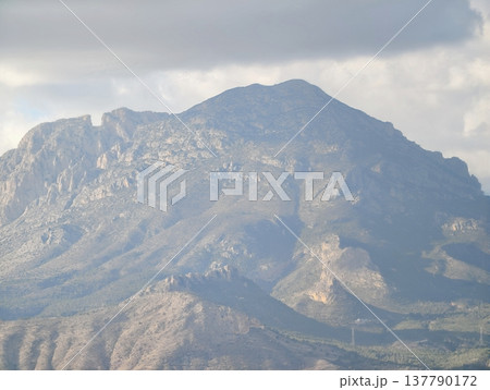 Large Summit With Cloud Shadows, Imposing Peak Glowing Softly Amidst Drifting Clouds And Rugged Ridges 137790172
