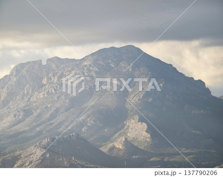 Rough Mountain Surface Highlighted By Sediment Layers And Cloud Shadows For Educational Geological Exploration 137790206