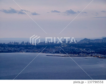 Coastal Towers Glow At Dusk, Urban Highrise Buildings Line Coast As Daylight Fades And Night Approaches Coastal Towers Glow At Dusk, Urban Highrise Buildings Line Coast As Daylight Fades And Night Approaches 137790558