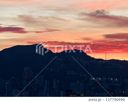 Dramatic Evening Silhouette Of Mountains Against Peaceful City Skyline With Distant Lights Dramatic Evening Silhouette Of Mountains Against Peaceful City Skyline With Distant Lights 137790690