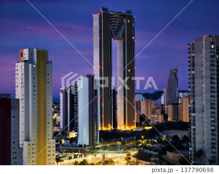 Illuminated City Skyline During Evening With Bustling Avenue And Reflective Glass Surfaces 137790698