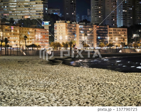 Peaceful Night View Of Glowing Urban Shoreline With Distant Highrise Buildings And Calm Waters Peaceful Night View Of Glowing Urban Shoreline With Distant Highrise Buildings And Calm Waters 137790725