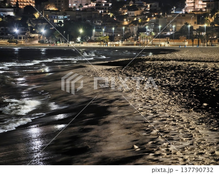 Sea Waves Glow Under City Illuminations, Rolling Ocean Waves Mirror Urban Lights At Nighttime Mood 137790732