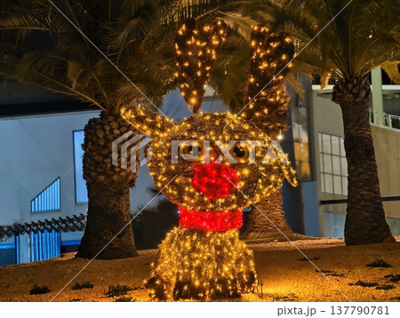 Golden Festive Dog, Brightly Glowing Golden Dog Figure Surrounded By Palm Trees And Holiday Lighting 137790781
