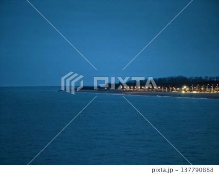 Twilight Distant Shoreline With Faint Lights Along Calm Sea And Long Blue Horizon Under Soft Evening Twilight Distant Shoreline With Faint Lights Along Calm Sea And Long Blue Horizon Under Soft Evening 137790888
