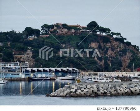 Sea Port With Rocky Surroundings, Marina Nestled By Cliffs Featuring Breakwater And Anchored Boats 137790960