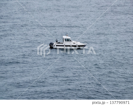 Silent White Boat Amidst Tranquil Blue Waters, Isolated Vessel On Sea Under Overcast Skies Conveying Solitude Silent White Boat Amidst Tranquil Blue Waters, Isolated Vessel On Sea Under Overcast Skies Conveying Solitude 137790971