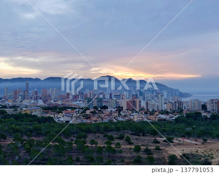 Urban Skyline Vista, Vivid Urban Horizon Featuring Mountain Backdrop And Layered Cloud Formations 137791053
