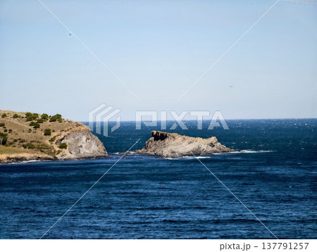 Simple Artistic Portrayal Of Lone Rock In Expansive Nautical Horizon With Distant Greenery 137791257