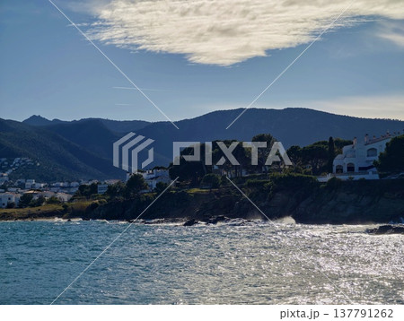 Calm Waters Reflect Distant Mountain Views, Peaceful Bay With Rocky Shores And Lush Hills In Daylight Calm Waters Reflect Distant Mountain Views, Peaceful Bay With Rocky Shores And Lush Hills In Daylight 137791262