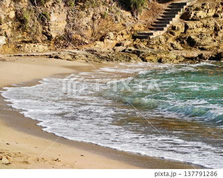 Hidden Sandy Bay With Clear Waves, Secluded Shoreline Featuring Rocky Stairs And Vibrant Waters Hidden Sandy Bay With Clear Waves, Secluded Shoreline Featuring Rocky Stairs And Vibrant Waters 137791286