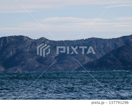 Serene Ocean Scenery, Calm Mountain Islands Above Sea, Gentle Waves And Sky With Clouds Above Islands 137791296
