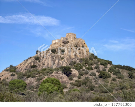 Old Stone Fortress Atop Rugged Slope, Medieval Ruins Perched On Remote Hillside Bathed In Sunlight 137791300
