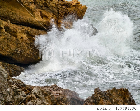 Powerful Ocean Spray Collides With Sharp Rocks Generating Tumultuous Foam And Dynamic Movement 137791336