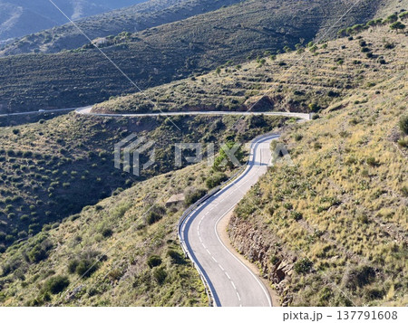 Winding Highway Amid Sunlit Hills, Sunlit Hilly Landscape With Twisting Road And Distant Ridges Winding Highway Amid Sunlit Hills, Sunlit Hilly Landscape With Twisting Road And Distant Ridges 137791608