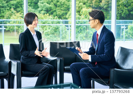 採用面接で面接官の質問に答えながら自己PRをする就活生の女性とメモを取る担当者の男性 137793268