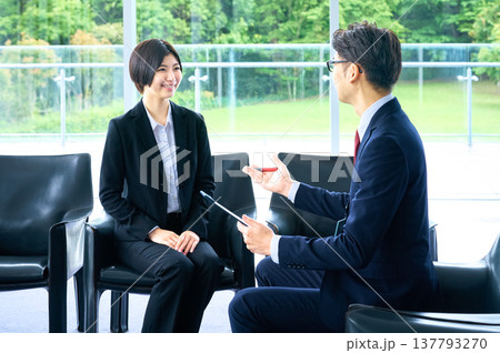 採用面接で自己PRをするスーツ姿の女性とメモを取る面接官の男性 137793270
