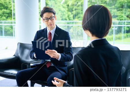 採用面接で求職者の話を真剣な表情で聞く面接官の男性とスーツの女性 137793271
