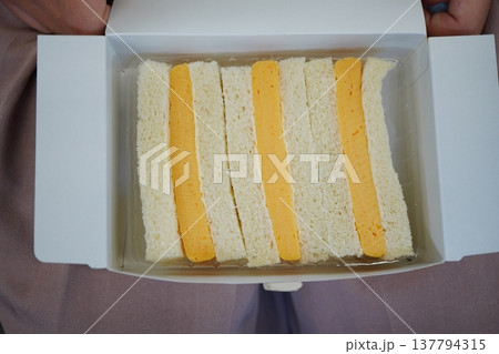 箱に入ったチーズサンドイッチの俯瞰写真。柔らかい食パンと厚切りチーズのシンプルなサンドイッチ。 箱に入ったチーズサンドイッチの俯瞰写真。柔らかい食パンと厚切りチーズのシンプルなサンドイッチ。 137794315
