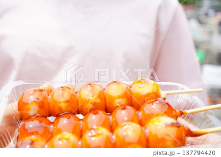 みたらし団子の串団子を透明容器に入れた日本の和菓子。甘辛いタレがかかった団子のクローズアップ。 137794420