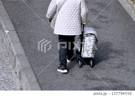 日本の横浜都市景観カートの高齢女性(マスク姿)、段差や隙間でカートはガタガタ揺れ歩きにくい…人生とは 137794558