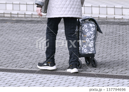 日本の横浜都市景観カートの高齢女性(マスク姿)、段差や隙間でカートはガタガタ揺れ歩きにくい…人生とは 137794696