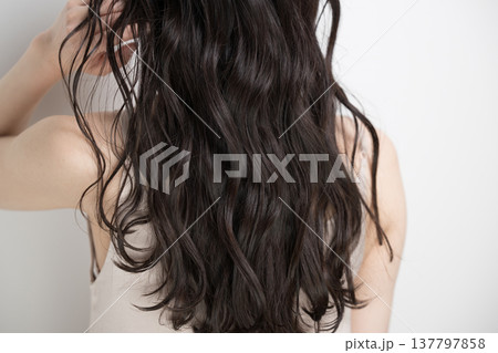 白背景に髪をなびかせるロングヘアでパーマの女性　顔無しの後ろ姿 137797858