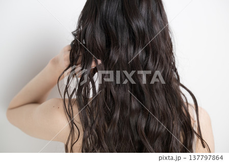 白背景に髪をなびかせるロングヘアでパーマの女性　顔無しの後ろ姿 137797864