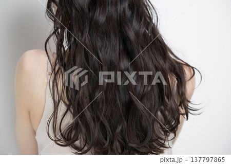 白背景に髪をなびかせるロングヘアでパーマの女性　顔無しの後ろ姿 137797865