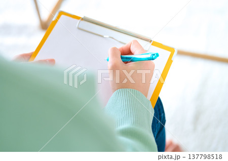 クリップボードに記入する女性の手元　問診票やアンケート、カウンセリングのイメージ 137798518