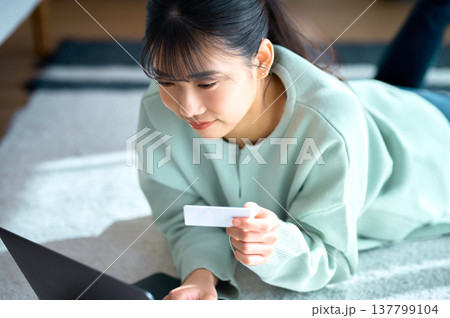 パソコンを見ながらクレジットカード情報を入力する女性のアップ パソコンを見ながらクレジットカード情報を入力する女性のアップ 137799104