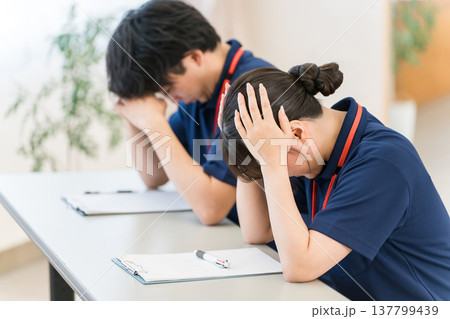 疲労,過労で頭を抱える介護士,介護職の男女スタッフ 137799439