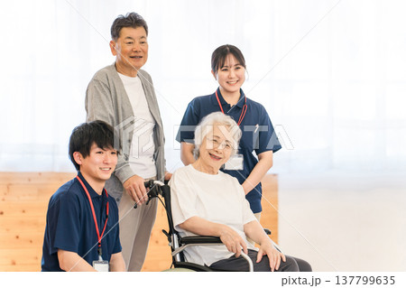 車椅子に乗るシニア女性・シニア夫婦と作業療法士・理学療法士の男女職員 車椅子に乗るシニア女性・シニア夫婦と作業療法士・理学療法士の男女職員 137799635