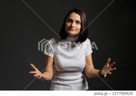 Young woman looking at camera with a confused expression and shrugging her shoulders in uncertainty. 137799920
