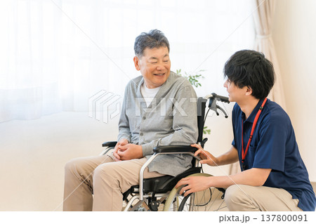 車椅子のシニア男性患者と介護士・ケアマネージャーの男性スタッフ（認知症・リハビリ） 137800091