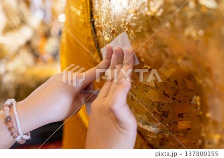 putting gold leaf on the back of the Buddha statue putting gold leaf on the back of the Buddha statue 137800155