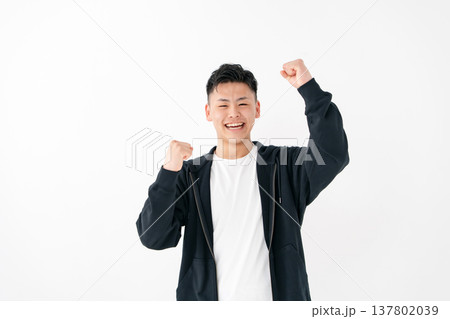 若い男性　カジュアル　ガッツポーズ 137802039