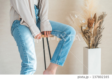 椅子に座るデニムを履いた女性 137802165