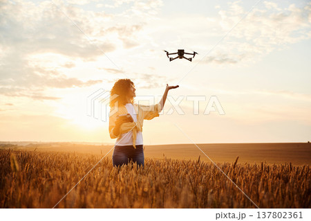 Controlling the drone. Beautiful woman is on the wheat agricultural field Controlling the drone. Beautiful woman is on the wheat agricultural field 137802361