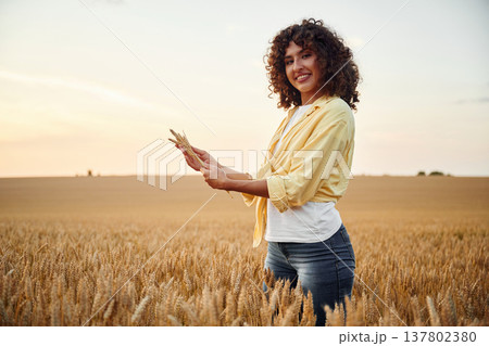 View from the side, holding wheat. Beautiful woman is on the agricultural field 137802380
