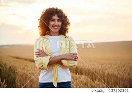 Standing with arms crossed. Beautiful woman is on the wheat agricultural field Standing with arms crossed. Beautiful woman is on the wheat agricultural field 137802391