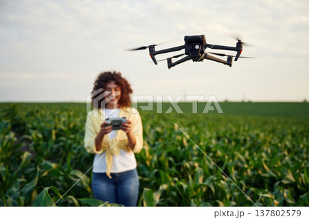 Little help from a drone, controlling it. Woman is on the corn agricultural field Little help from a drone, controlling it. Woman is on the corn agricultural field 137802579