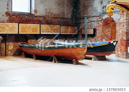 Wooden boats on display in an old brick building with stone walls in a historical location Wooden boats on display in an old brick building with stone walls in a historical location 137803053