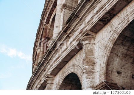 Close view of the Colosseum in Rome showing stone details and arches under blue sky Close view of the Colosseum in Rome showing stone details and arches under blue sky 137803109