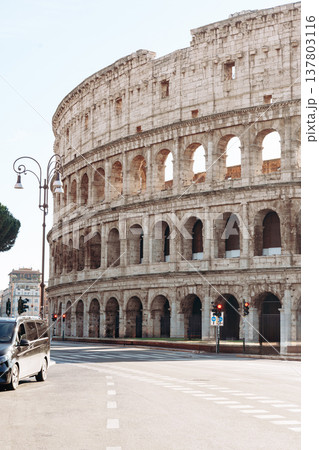 Exploring the ancient colosseum in Rome during a sunny day with passing cars nearby 137803116