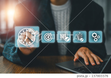 Business professional interacts with digital icons for time management and productivity on a virtual screen. 137803376