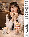 温かみのあるカフェでいちごパフェとコーヒーを楽しみながらウインクする可愛い若い女性 137803575