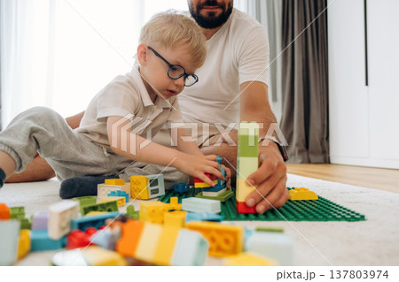 Father is playing in the room with his little son with construction sets Father is playing in the room with his little son with construction sets 137803974