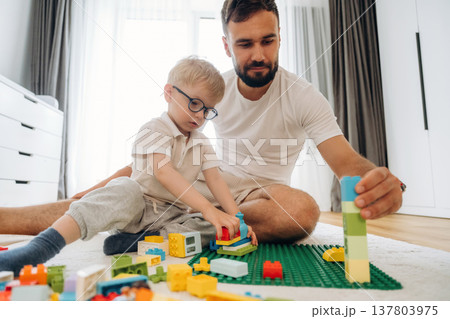 Father is playing in the room with his little son with construction sets Father is playing in the room with his little son with construction sets 137803975