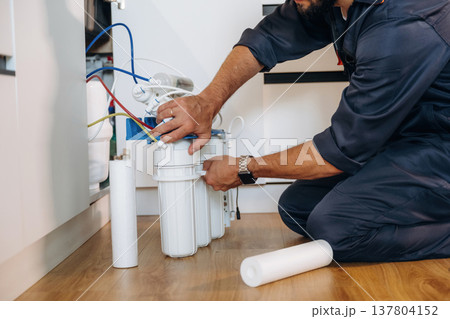 Installing new filters. Plumber working in the kitchen under the sink Installing new filters. Plumber working in the kitchen under the sink 137804152